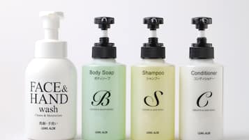 Cuatro botellas de productos de cuidado personal: jabón facial y de manos, gel de baño, champú y acondicionador.