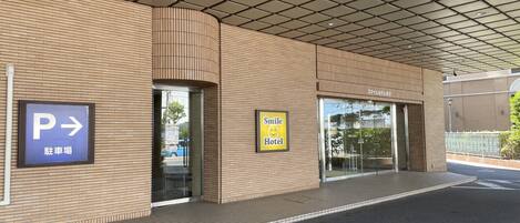 L'ingresso di un edificio con un'insegna per il parcheggio, la scritta Smile Hotel e un soffitto piastrellato.