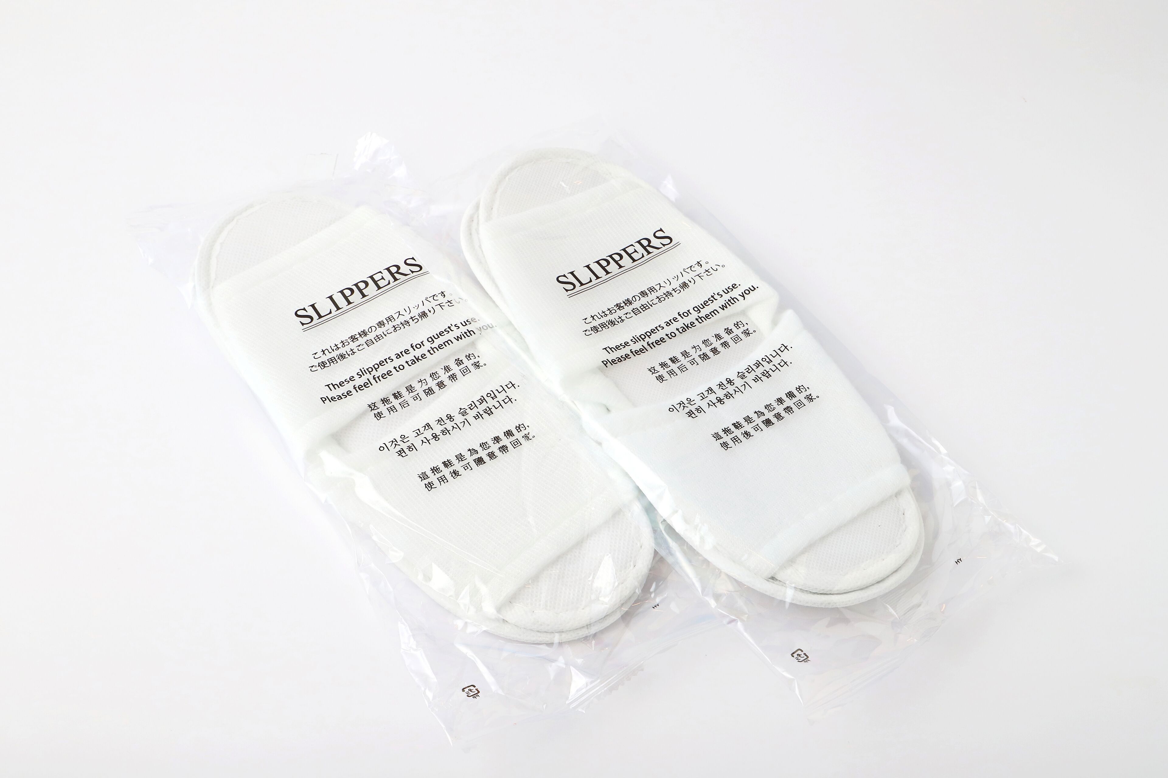 A pair of slippers in a plastic package with text on them.