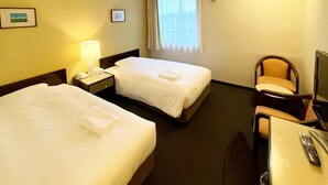 Habitación de hotel con dos camas, un escritorio, una silla, un televisor y una ventana con cortinas.