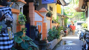 Una calle estrecha con un edificio que tiene un letrero, plantas en macetas y motocicletas estacionadas.