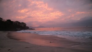 Una playa con olas y un atardecer.