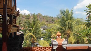 Un edificio tradicional con elaboradas esculturas, vistas a palmeras y una colina al fondo.