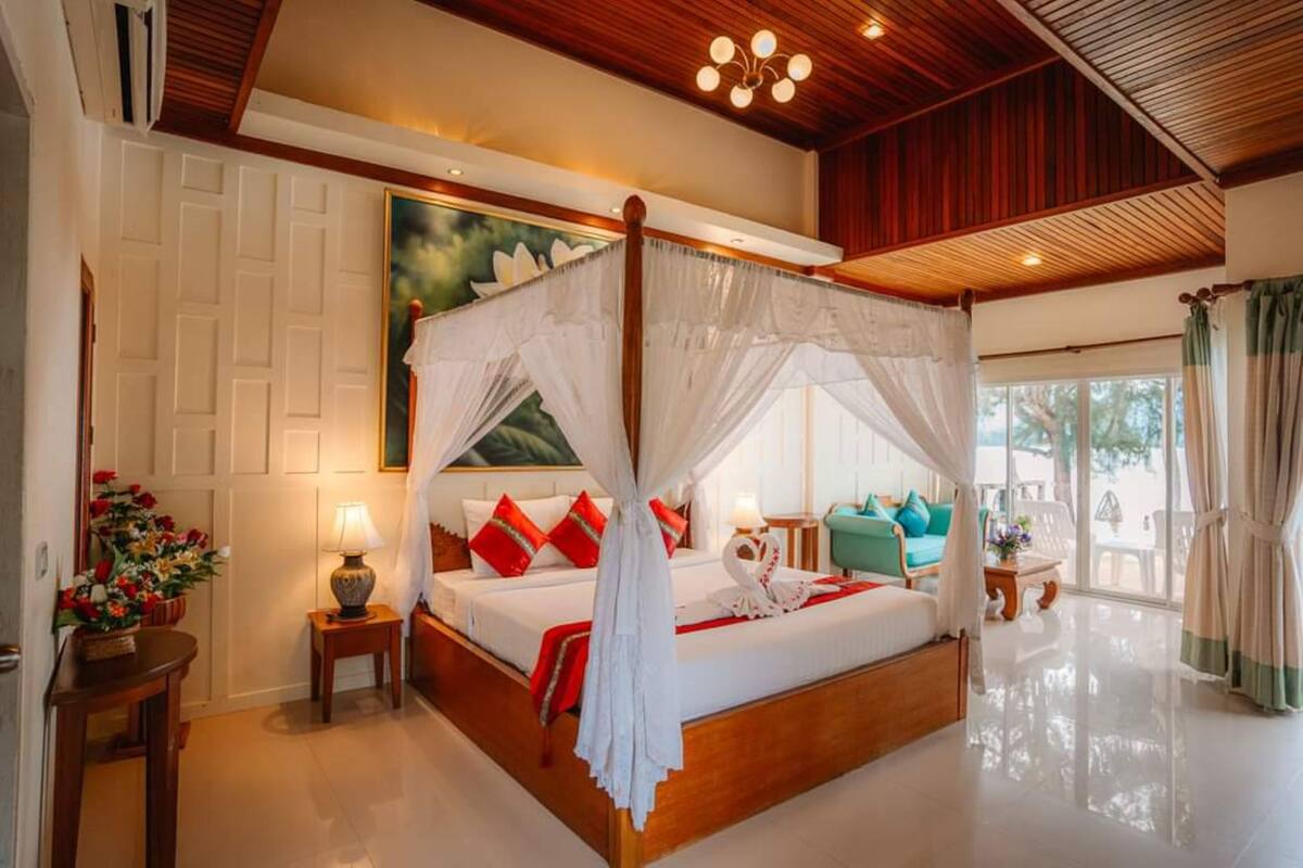 A spacious bedroom with a canopy bed, a large window, and a view of the outdoors.