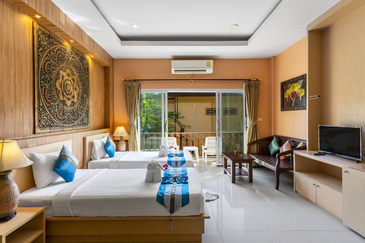 A hotel room with two beds, a TV, a balcony with a chair, and a desk.