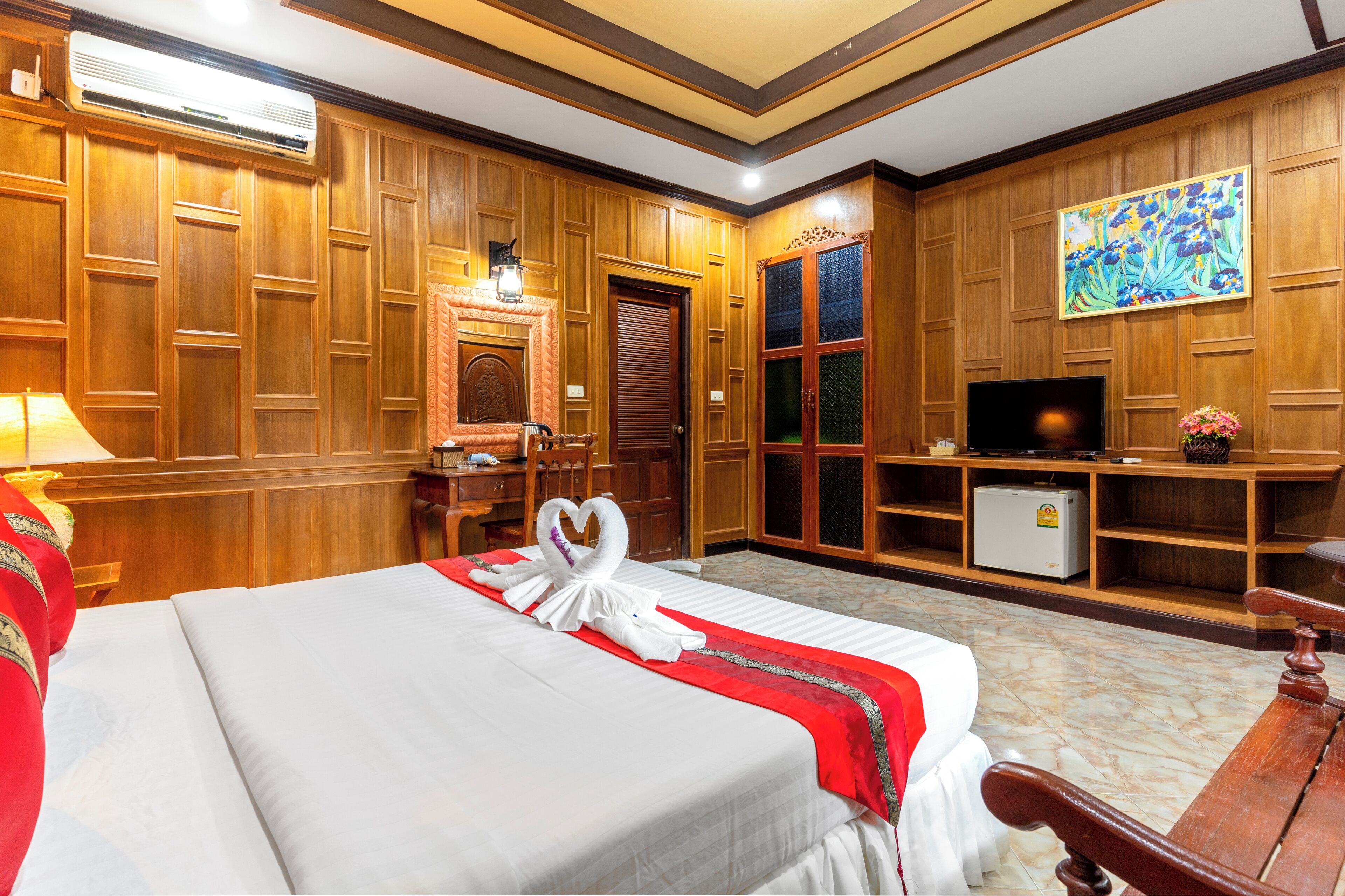 Ein Hotelzimmer mit einem großen Bett, Holzwänden, einem Fernseher, einem Kühlschrank und einem Gemälde an der Wand.