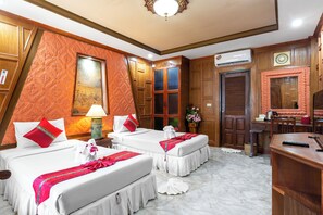 A hotel room with two beds, a desk, and a mirror.