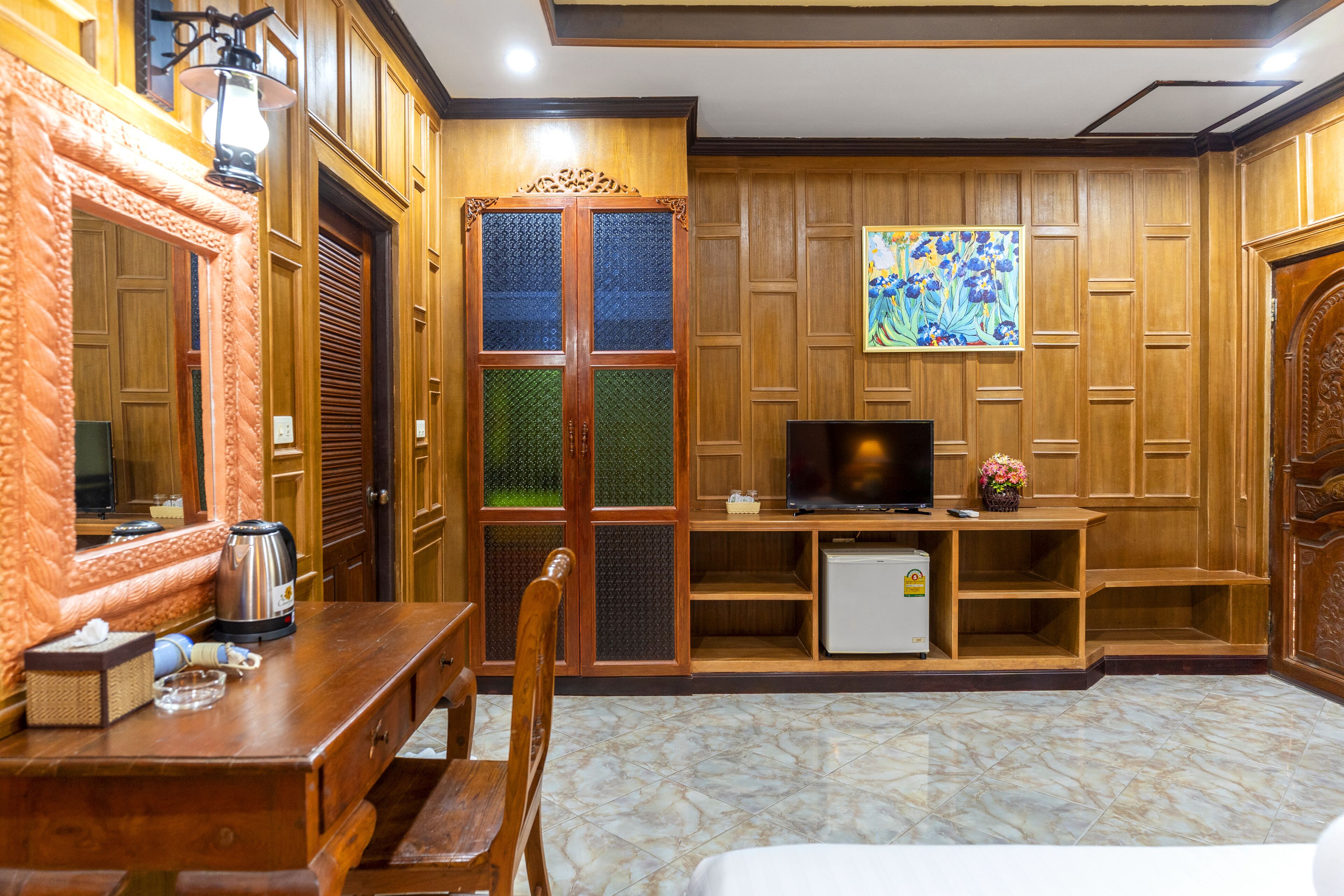 A hotel room with a wooden cabinet, a television, a small refrigerator, and a dining table with chairs.