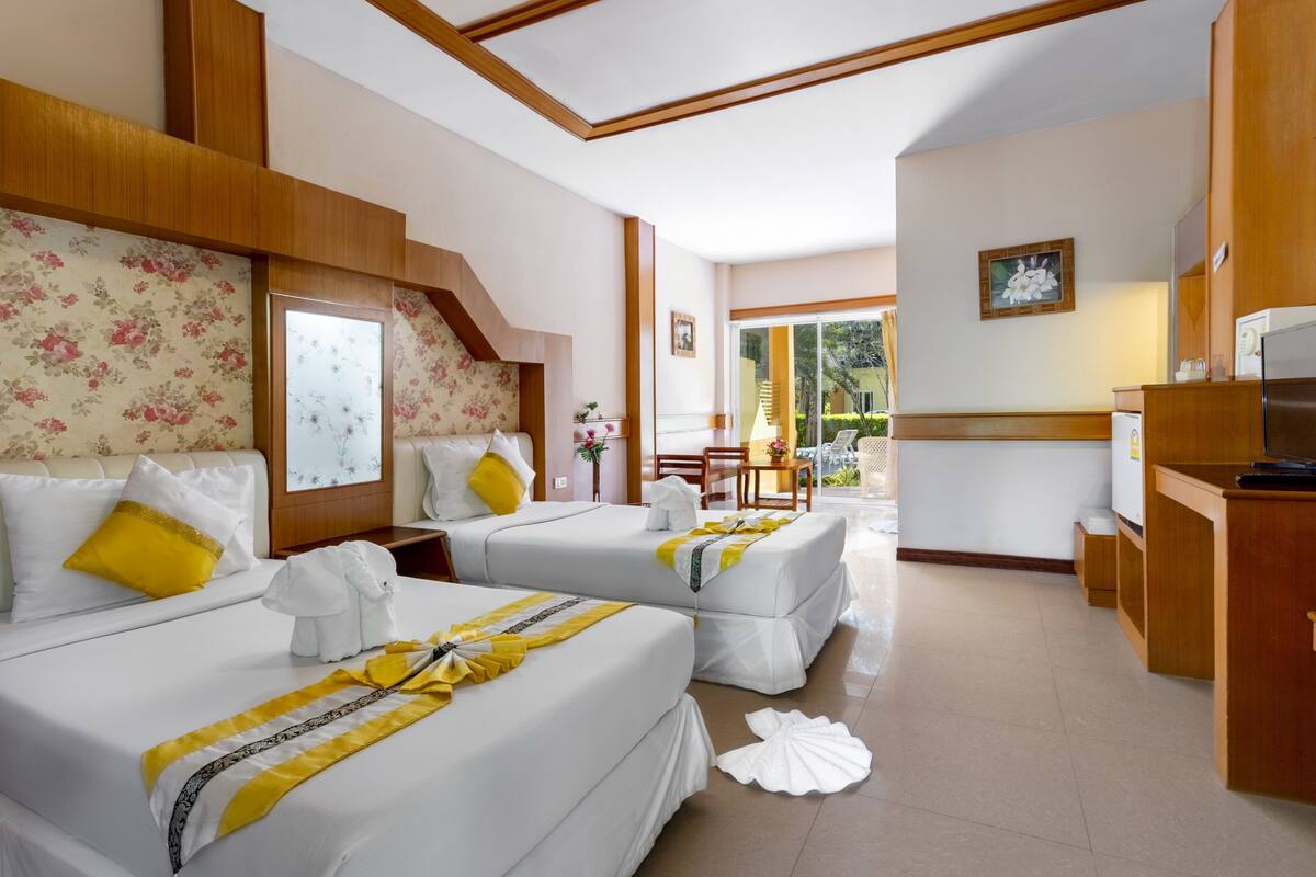 A hotel room with two beds, a small kitchenette, and a dining area with a view.