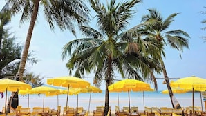 A beach with rows of wooden chairs and yellow umbrellas labeled 'Coco'. - Coconut Beach Resort (Ko Chang)