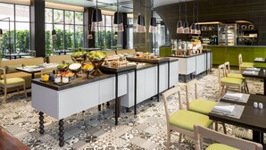 A modern restaurant with a central island, seating arrangements, and a kitchen area.