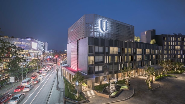 A modern building with a prominent 'U' logo, surrounded by a landscaped area with pathways and greenery.