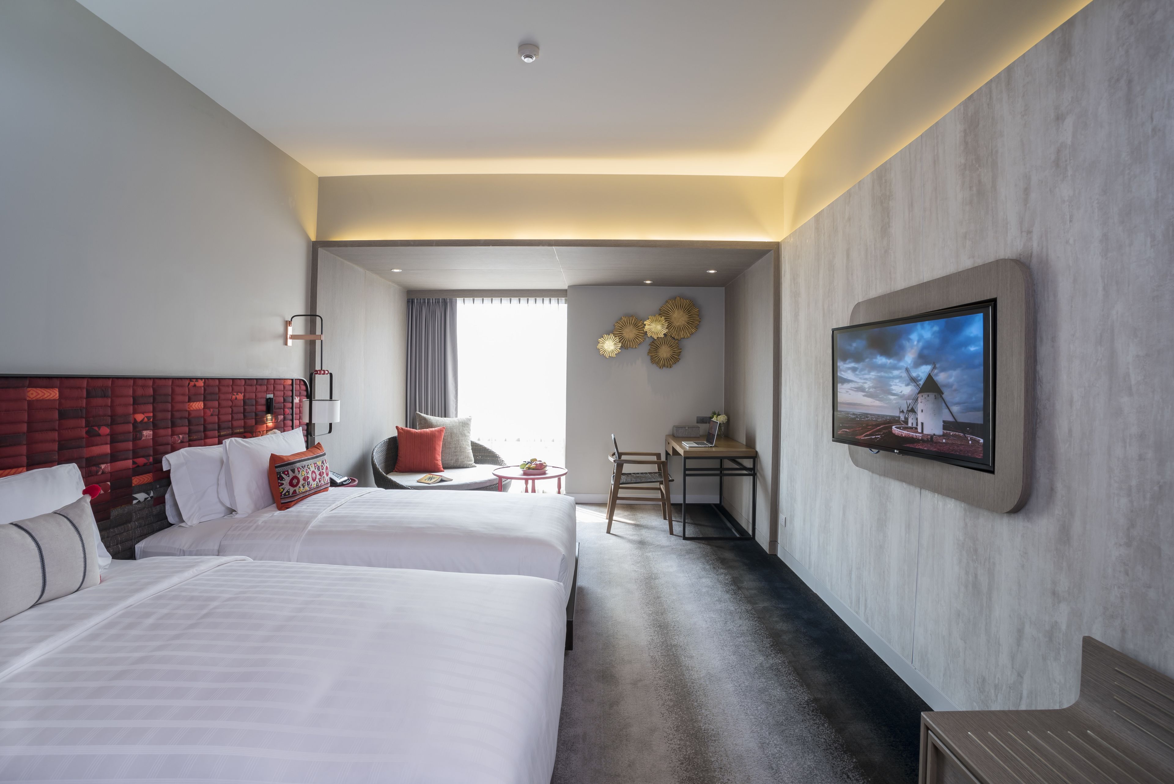 Une chambre d’hôtel avec deux lits, un bureau, une télévision et une vue sur l’extérieur.