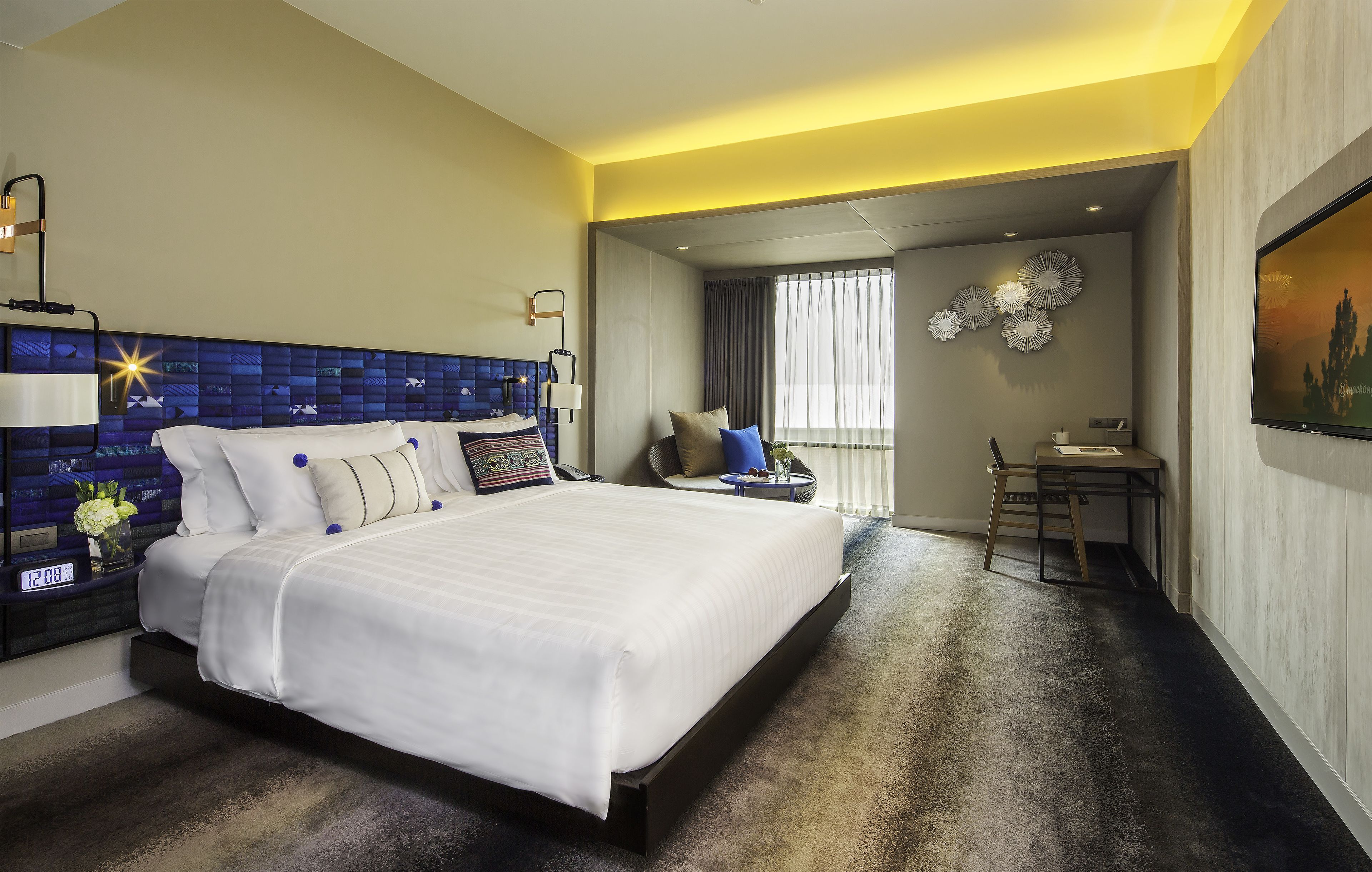 Una habitación de hotel moderna con una cama grande, una mesita de noche y un escritorio con silla.
