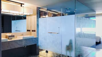 A modern bathroom with a glass-enclosed shower, a marble vanity, and patterned floor tiles.
