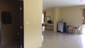 A hotel room with a desk, chair, and a refrigerator.