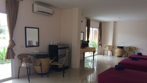 Ein Hotelzimmer mit Schreibtisch, zwei Sesseln, einem Computer und zwei Betten mit Handtüchern.