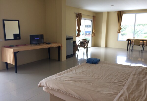 Una habitación de hotel con una cama, un escritorio con una computadora portátil, una silla y un ventanal con cortinas.