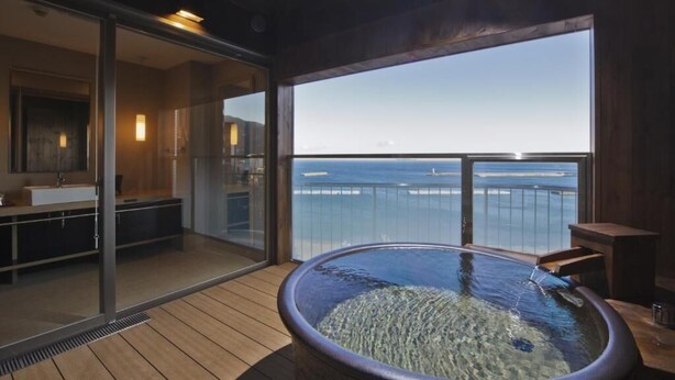 A modern bathroom with a glass-enclosed shower, a bathtub, and a view of the sea. - Atami Seaside Spa & Resort (Atami)