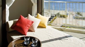 A balcony with a view of the sea, a bed with pillows, and two glasses on a tray. - Atami Seaside Spa & Resort (Atami)