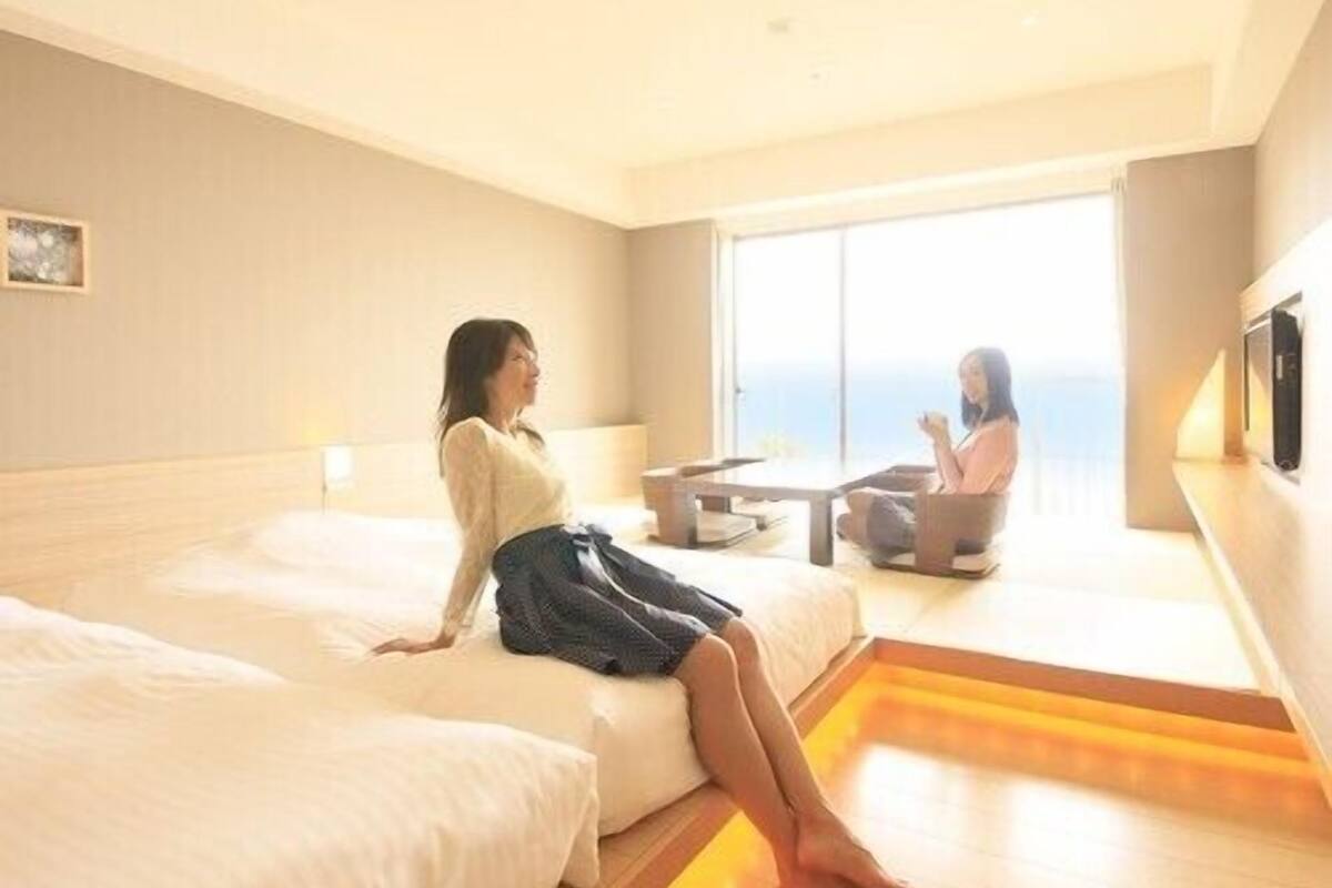 A hotel room with a large bed, a smaller bed, a desk, and a view of the outdoors.