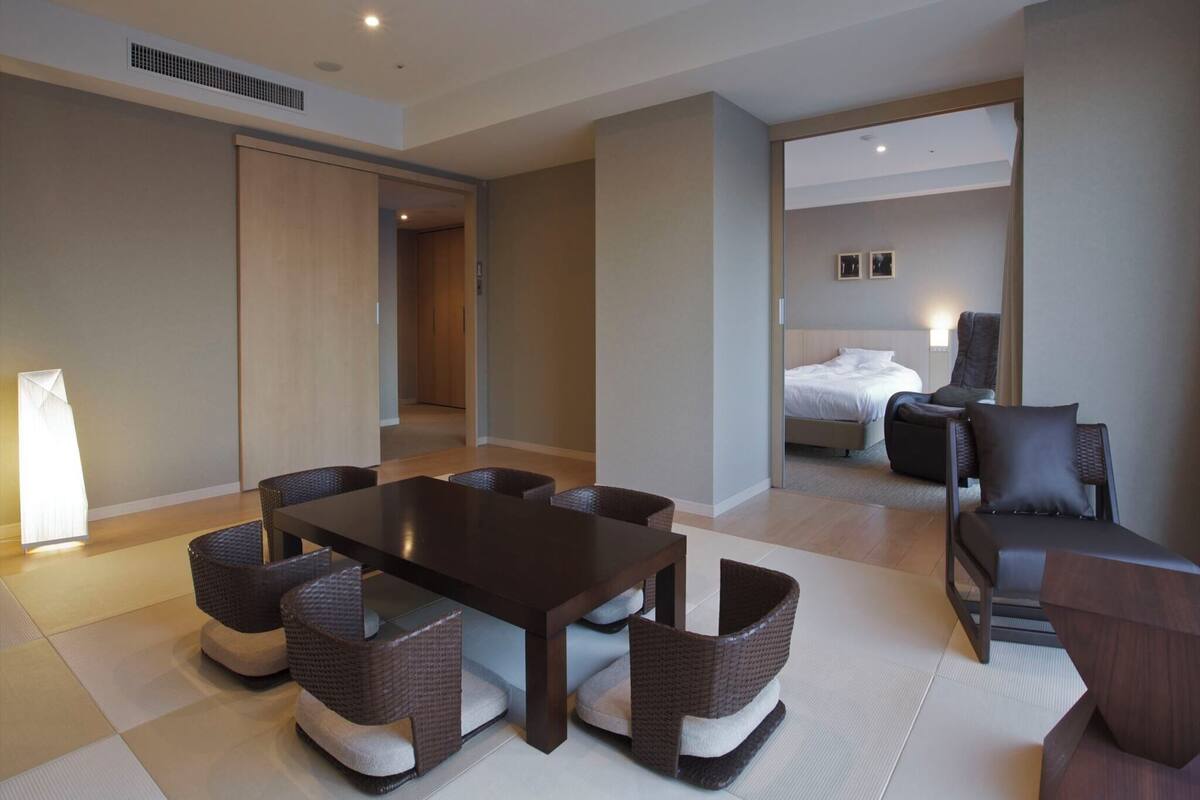 A modern hotel room with a dining area, a bed, and a bathroom.