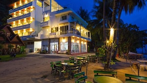 Un hotel de varios pisos con asientos al aire libre y vista a la playa.