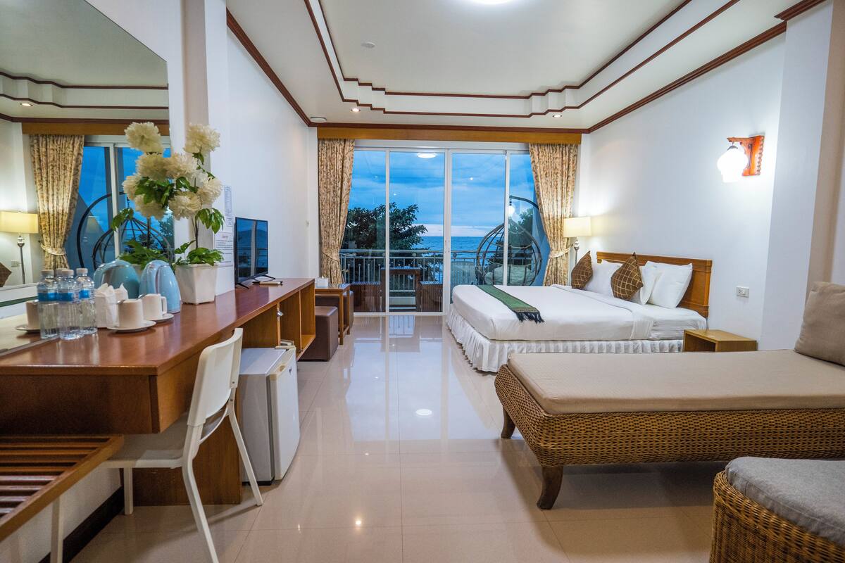 Una habitación de hotel con balcón, cama, escritorio y zona de comedor.