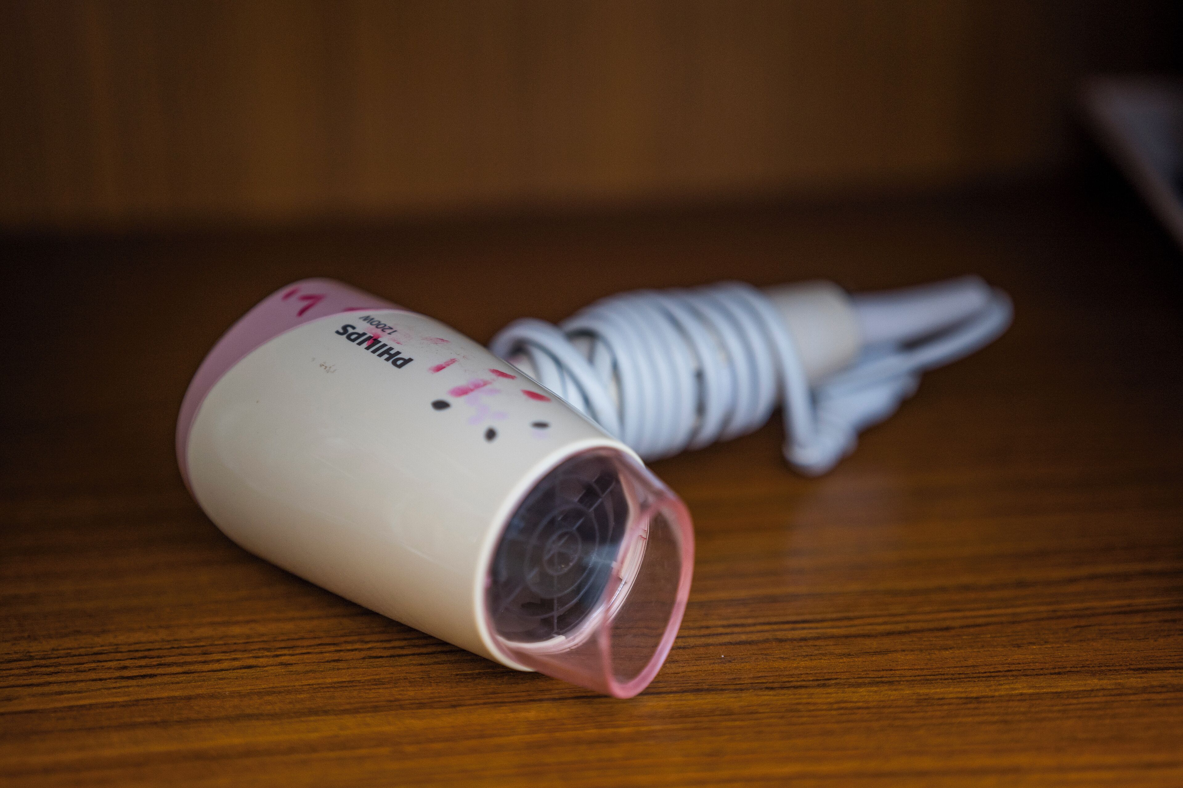 A cylindrical object with a pink and white design, lying on a wooden surface.