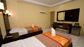 Une chambre d’hôtel avec deux lits, un bureau, une chaise, un t éléviseur et un appareil de climatisation.