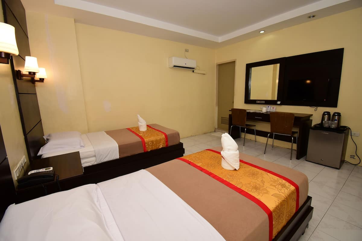 Een hotelkamer met twee bedden, een bureau, een stoel, een televisie en een airconditioning.