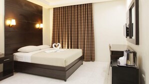 Una habitación de hotel con cama, mesitas de noche, cafetera y espejo.