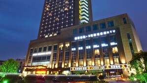 Un hôtel moderne à plusieurs étages, doté de grandes fenêtres et d’une enseigne lumineuse.