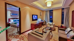 Une chambre d’hôtel équipée d’un lit, d’une télévision, d’un bureau, d’un canapé et d’une table basse.