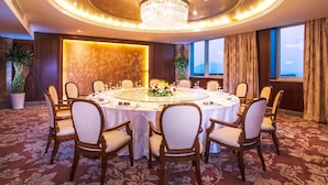Une table de salle à manger ronde, entourée de chaises, un lustre et un arrangement floral.