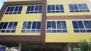 A multi-story building with a yellow facade and brown accents. - GIB Apartment (Surin)
