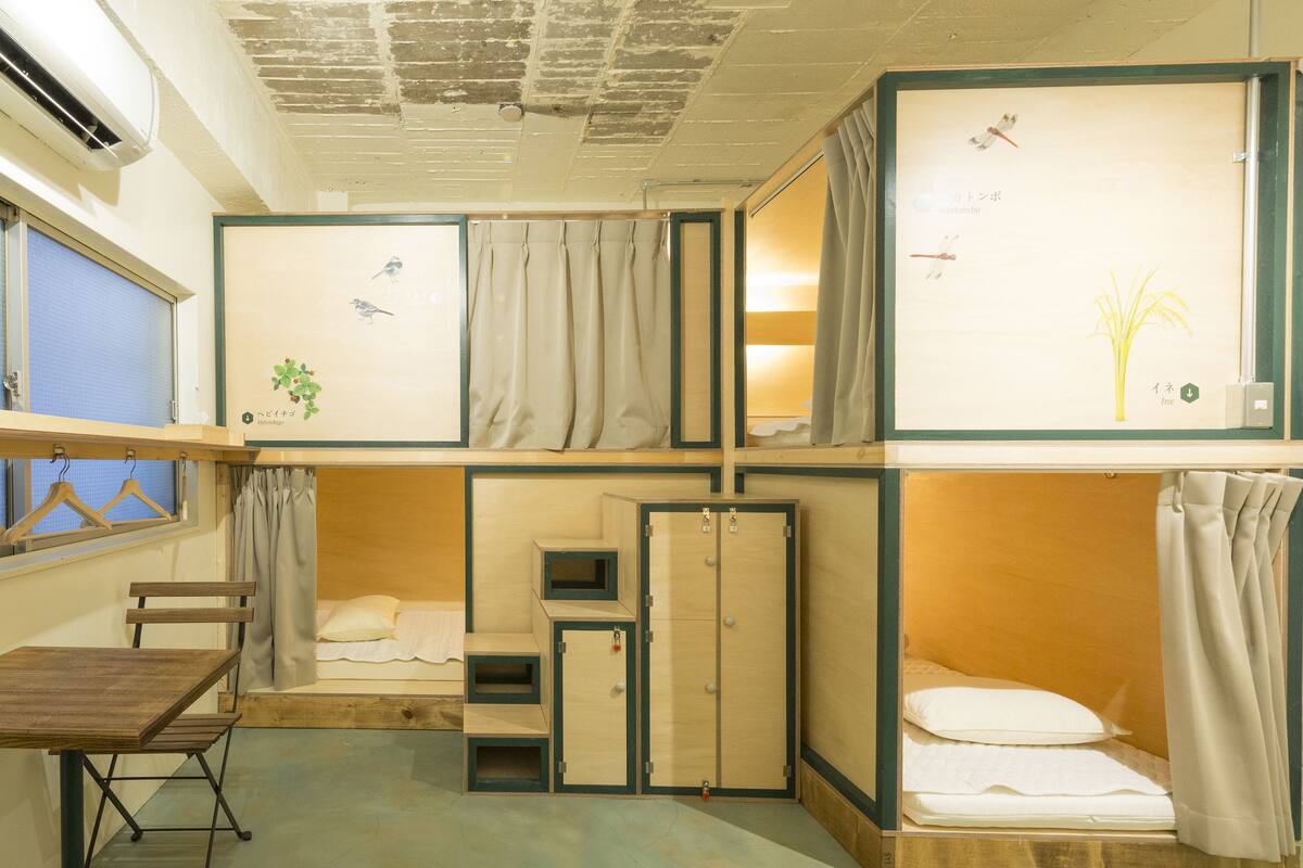 A compact room with a bunk bed, a small desk, and a wardrobe.