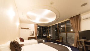 Une chambre d’hôtel avec deux lits, un bureau avec un ordinateur, une chaise et une grande fenêtre avec des rideaux.