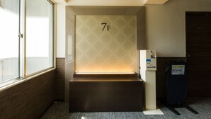 A hotel room with a large window, a wall-mounted number '7F', and a luggage trolley. - Ochanomizu Inn (Tokyo)