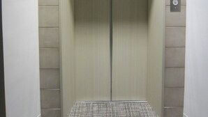 An elevator with a digital display showing the number 4, control buttons, and a metallic floor. - Ochanomizu Inn (Tokyo)