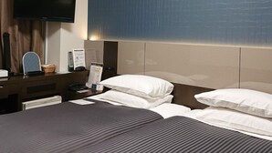 A hotel room with a large bed, a flat-screen TV mounted on the wall, a desk with a computer, and a nightstand with a lamp. - Ochanomizu Inn (Tokyo)
