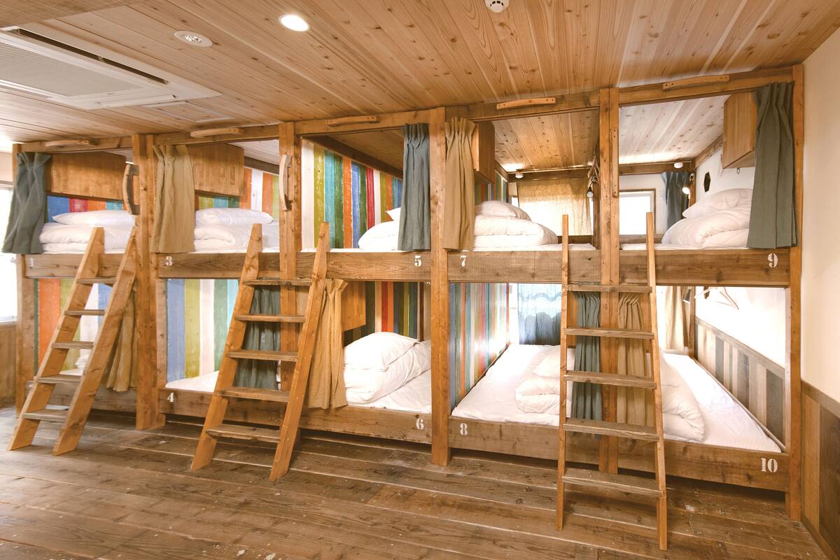 A cabin with bunk beds numbered 3 to 10, wooden ladders, and colorful curtains.