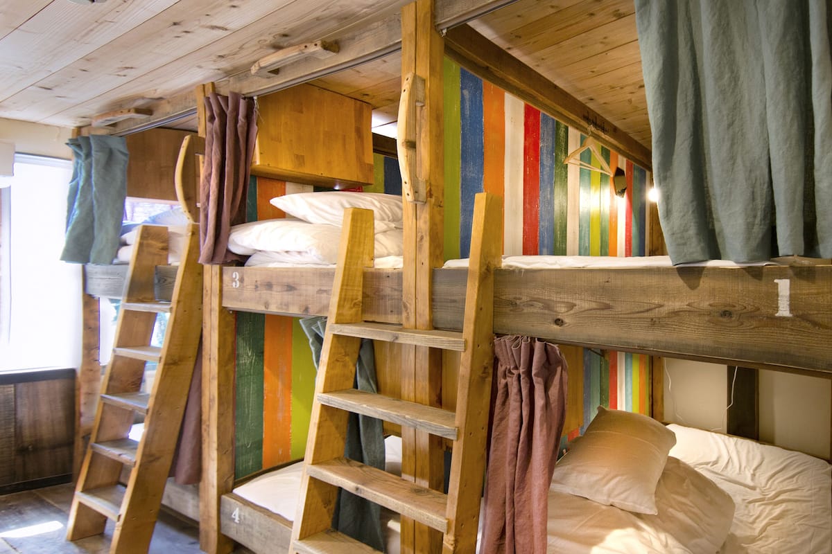 A bunk bed room with wooden ladders and colorful striped walls.