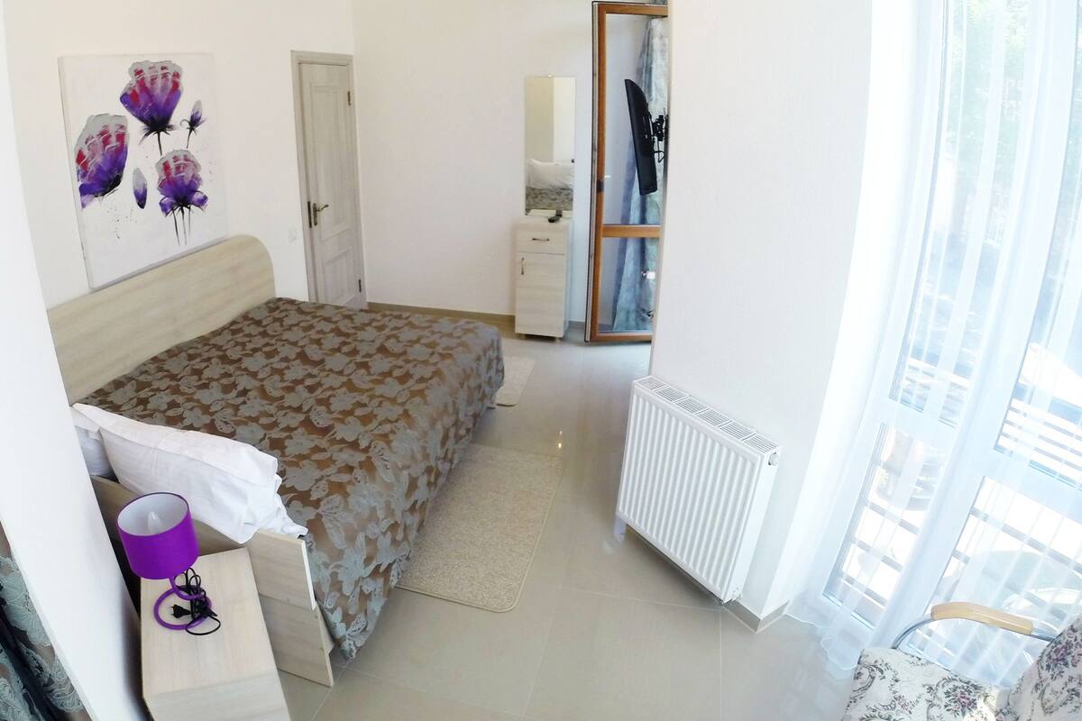 Une chambre à coucher avec un lit, une commode, un miroir et un radiateur.