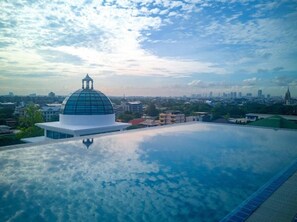 Un bâtiment moderne doté d’un dôme et d’une piscine sur le toit offrant une vue panoramique sur la ville.