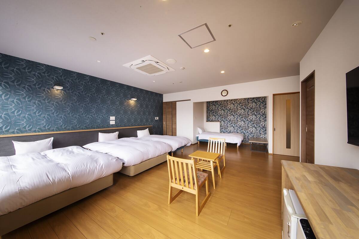 Ein Hotelzimmer mit zwei Betten, einem Holztisch und einem Fernseher.