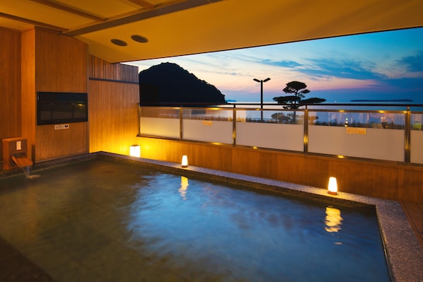 Baño de aguas termales con vista a la montaña y al atardecer.