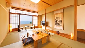 A traditional Japanese room with tatami flooring, a low wooden table, and a view of the sea. - Resort Hotel Mihagi (Hagi)
