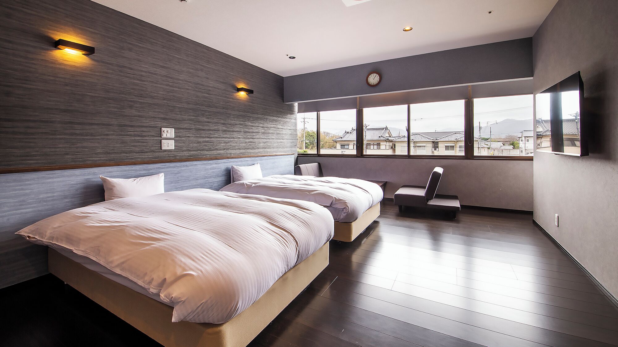A modern hotel room with a large bed, a seating area, and a view of the city.