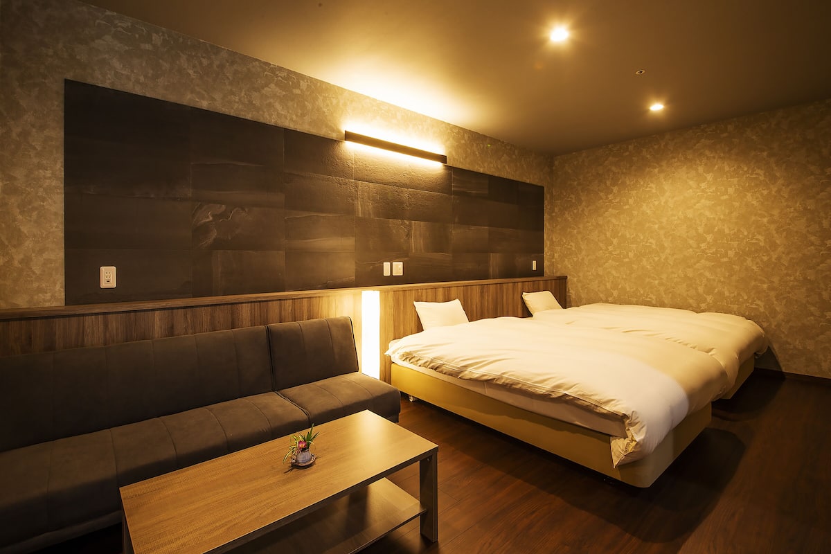 Ein modernes Hotelzimmer mit einem großen Bett, einer Couch und einem kleinen Tisch.